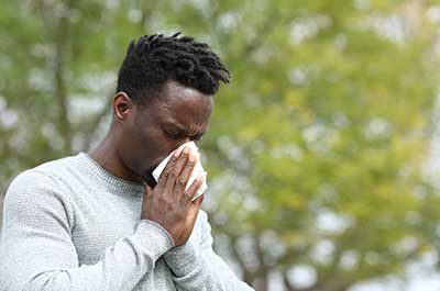 man blowing nose outside