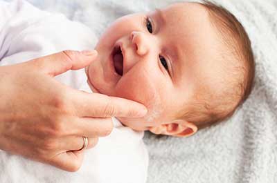 mom putting lotion on baby