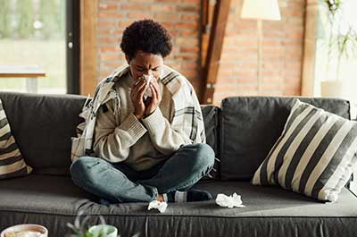 person blowing nose on couch