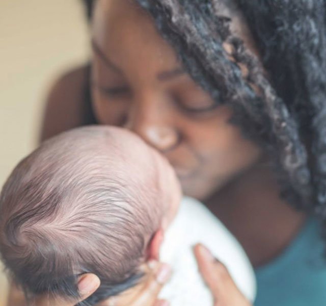 mother kissing new baby