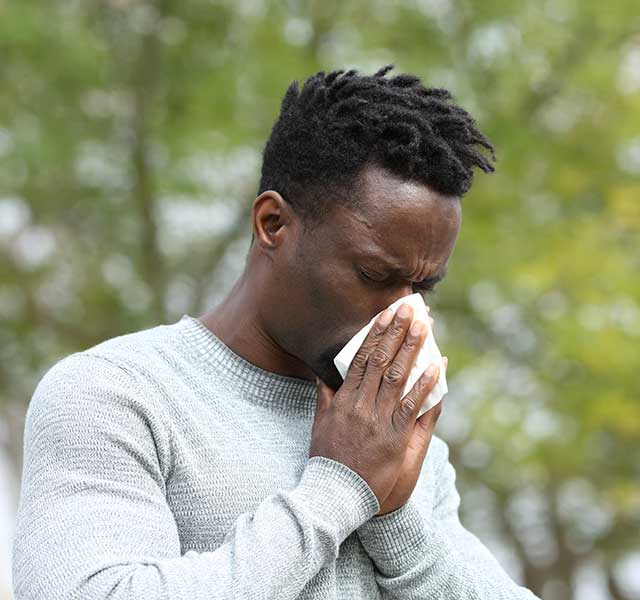 man blowing nose outside