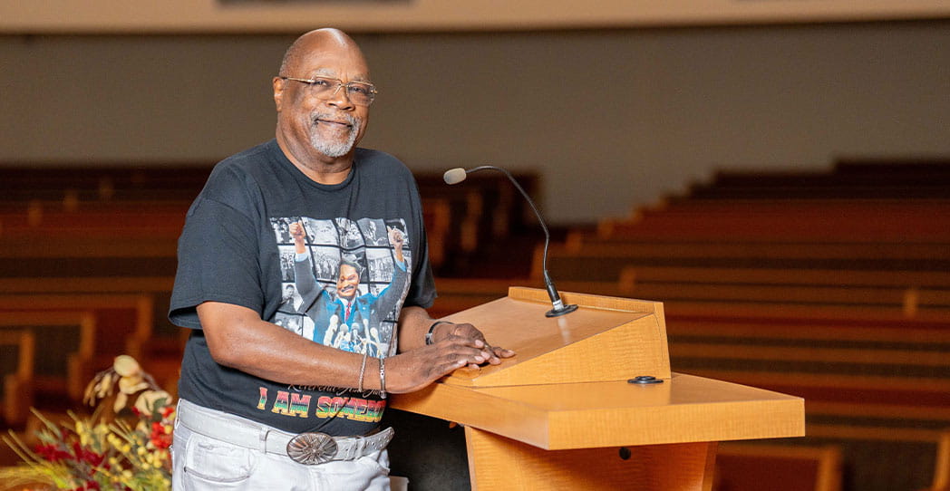 EP patient Reverend Anthony standing at the speaker podium at his church
