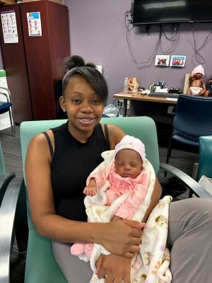 A WIN Network participant holds her baby while seated in the group prenatal care room, waiting to be seen by her certified nurse midwife.