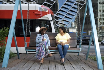 Two women sitting on swing talking