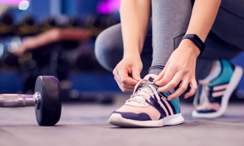Concept image of person tying tennis shoes in workout facility