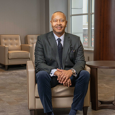 Marcus posed sitting in a chair wearing a suit