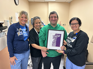 Photo of artist Dylan Somberg with his artwork and Henry Ford Health care team.