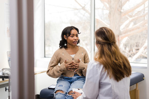black woman speaking with a doctor in a clinical setting