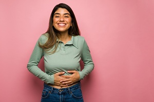 Woman smiling while holding stomach 